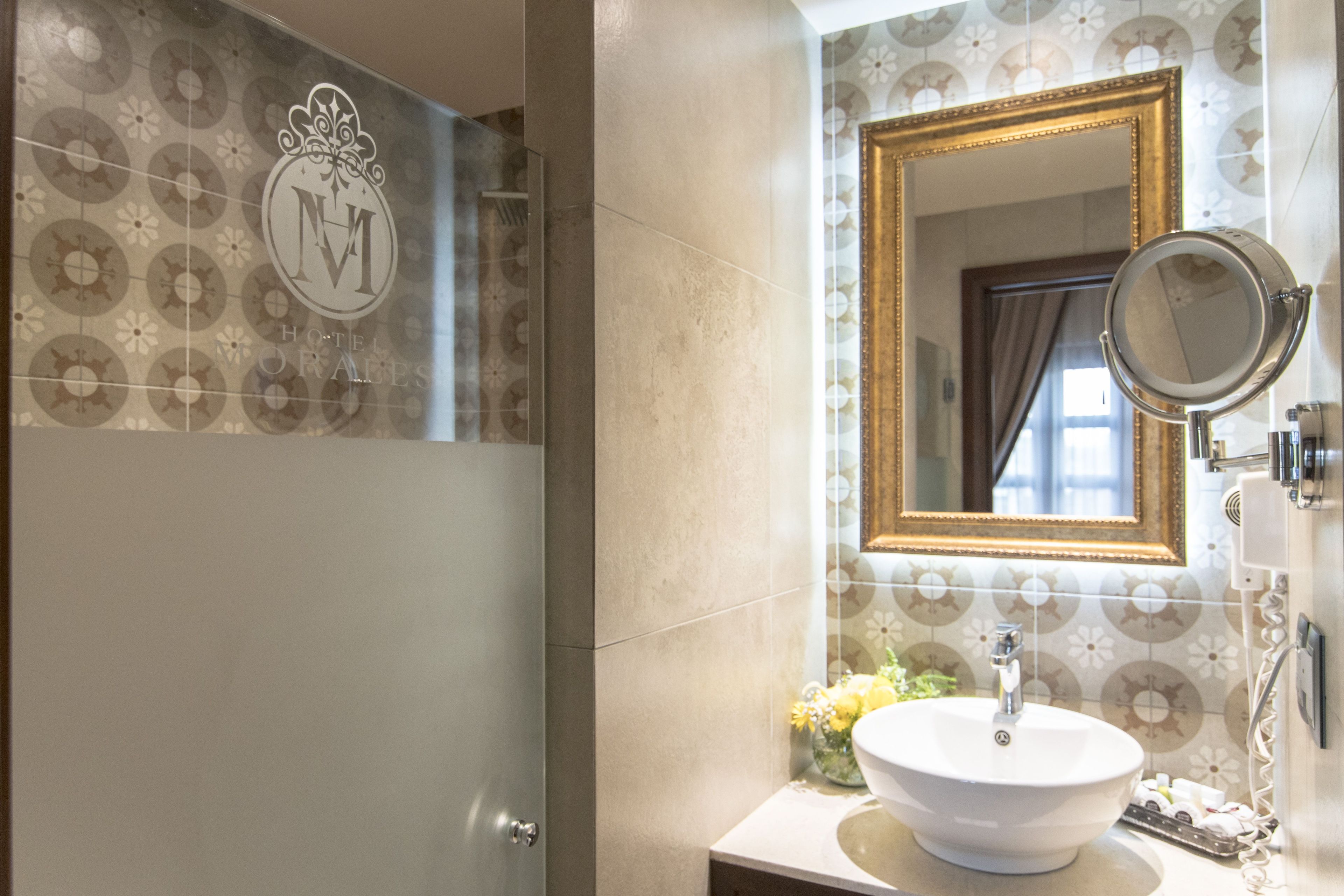 A bathroom with a large mirror, a sink, and a shower.