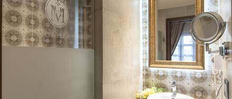 A bathroom with a large mirror, a sink, and a shower.