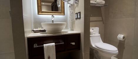 A modern bathroom with a white sink, a large mirror, a toilet, and a towel rack.