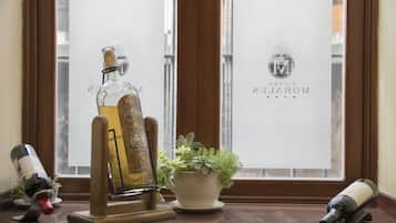 A bottle of alcohol on a wooden stand, a potted plant, and a window with frosted glass.
