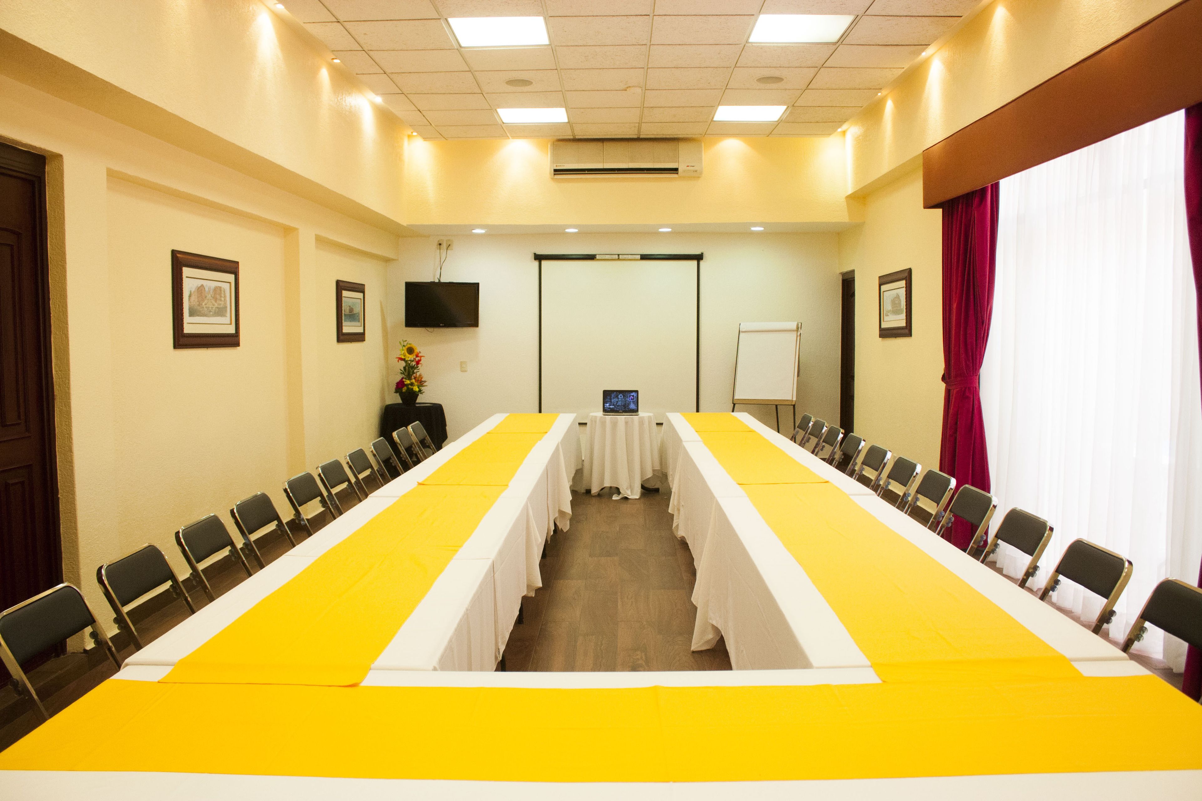 A conference room with a long table, chairs, a projector screen, and a whiteboard.