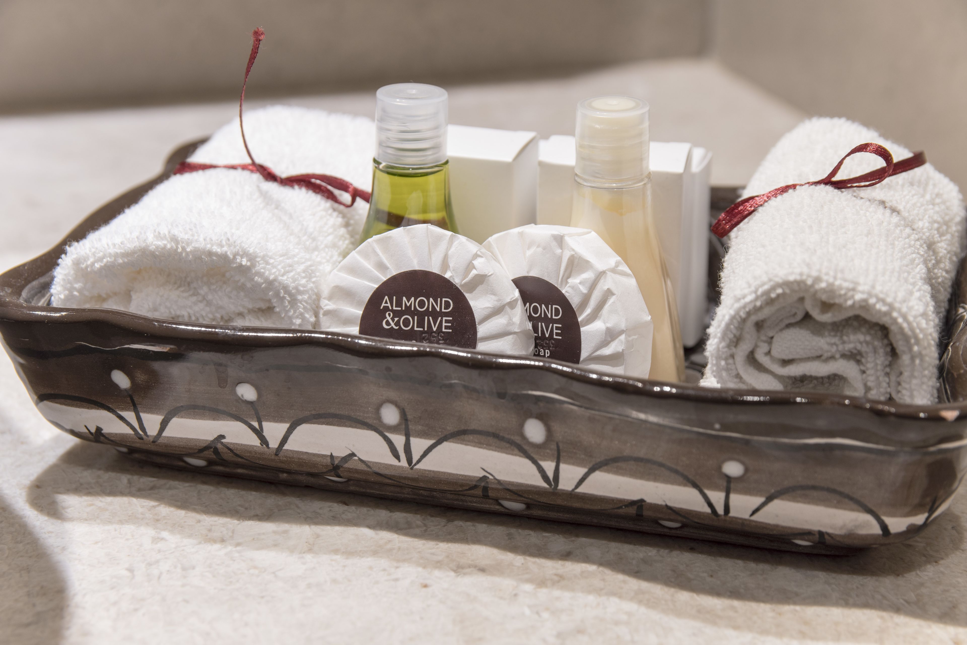 A tray with rolled towels, bottles of lotion, and a box.