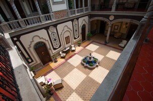 Un patio con una fuente, zona de estar y un piso con diseño de tablero de ajedrez.