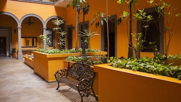A courtyard with a bench, planters, and a tiled floor.