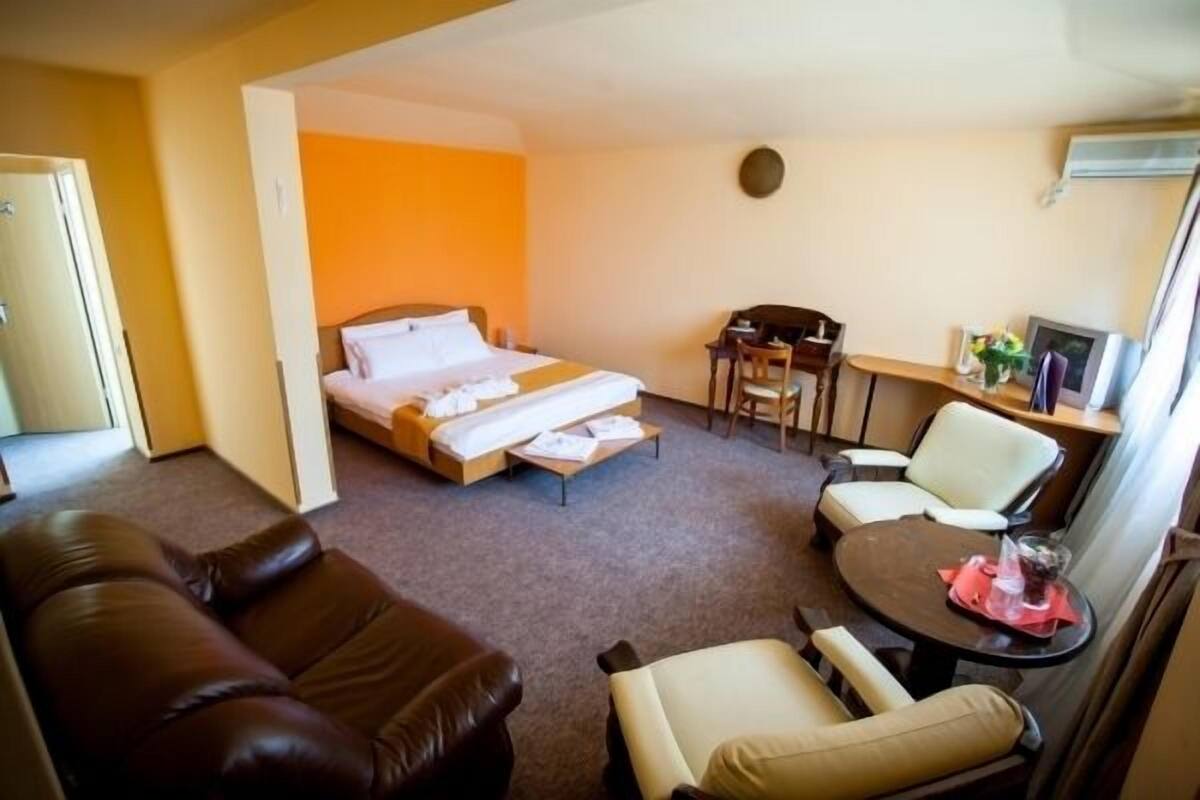 Una habitación de hotel con una cama, un escritorio, dos sillas y un sofá.