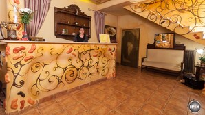 A reception area with a decorative wall, a reception desk, a sofa, and a staircase. - Deja Vu Pension (Cluj-Napoca)