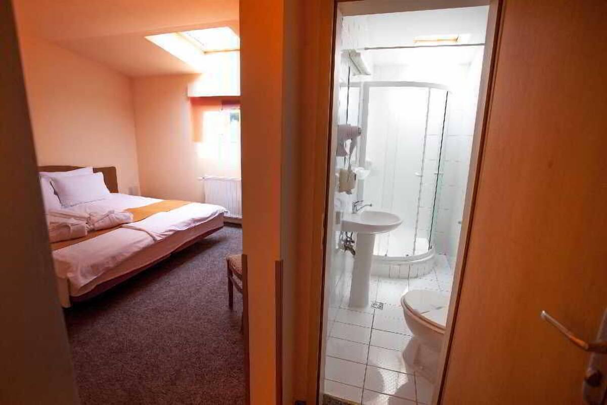 Un dormitorio con una cama, una mesita de noche pequeña y un ventanal.