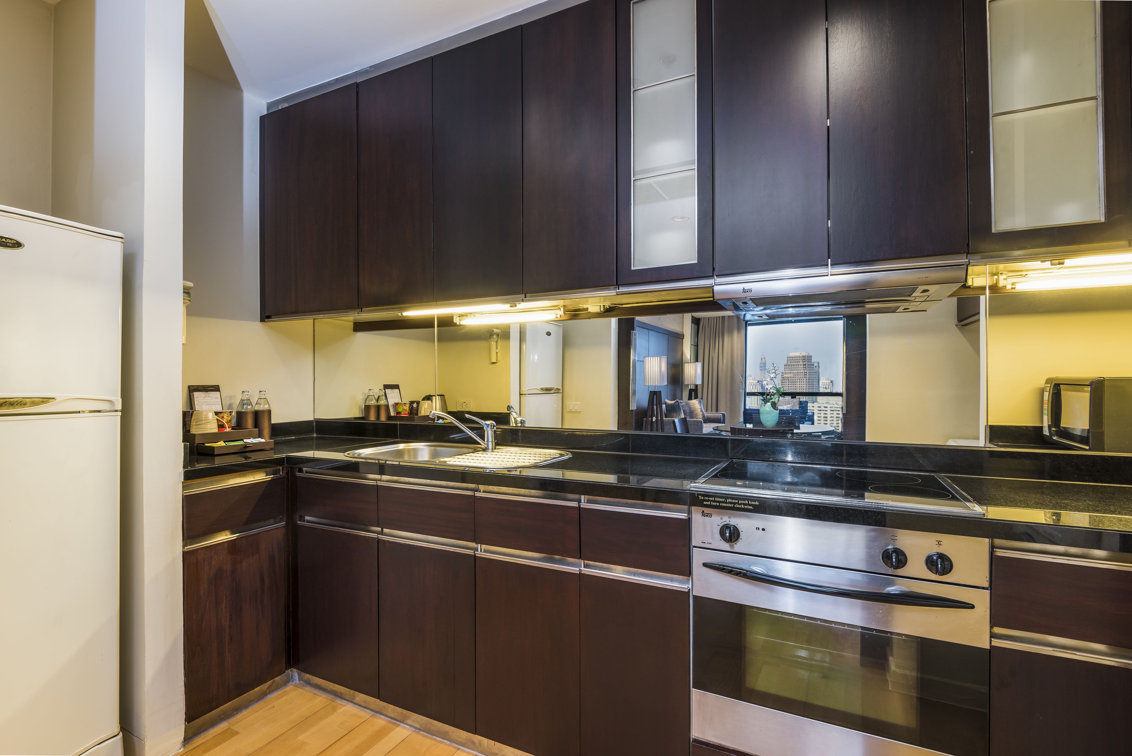 A modern kitchen with dark wood cabinets, stainless steel appliances, and a black countertop.