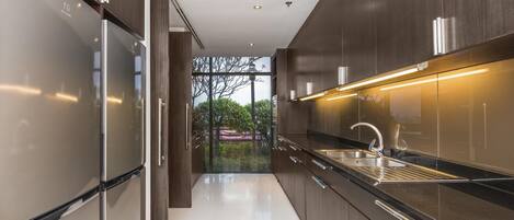 Una cocina moderna con electrodomésticos de acero inoxidable, armarios de madera oscura y un amplio ventanal con vistas a zonas verdes.