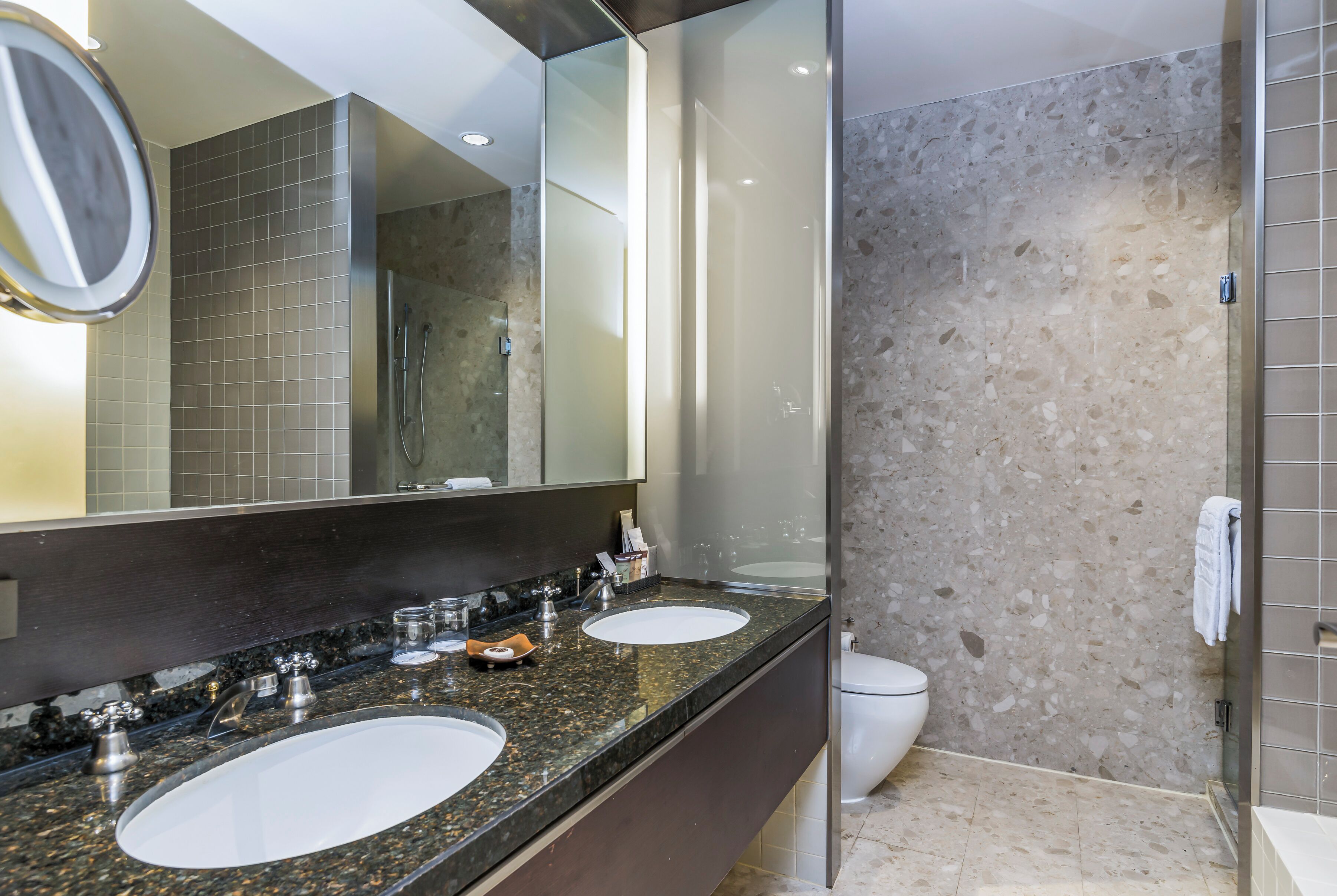 Un baño moderno con dos lavamanos, un espejo grande y una cabina de ducha con mampara de cristal.