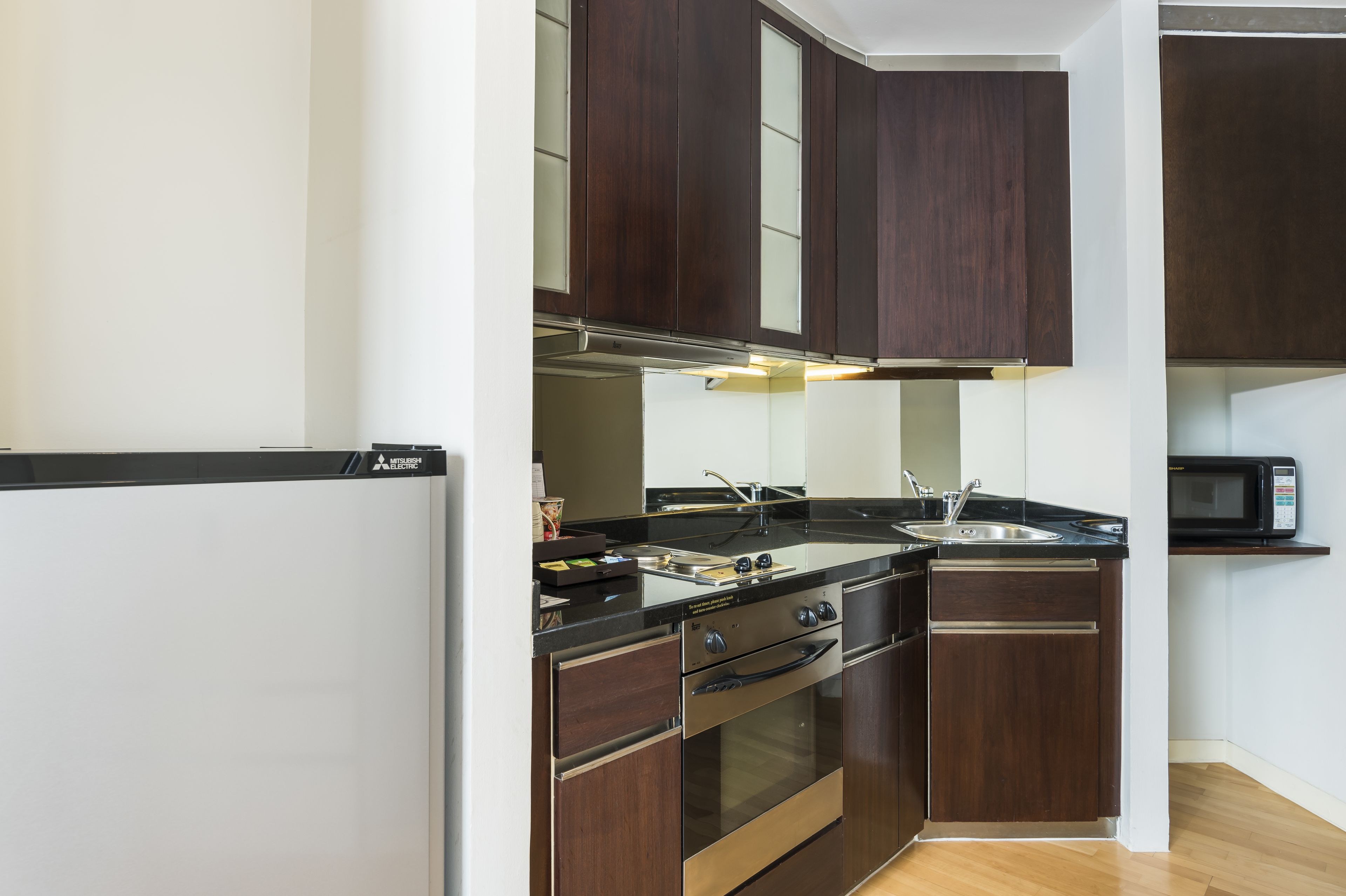 A modern kitchen with dark wood cabinets, stainless steel appliances, and a black countertop.