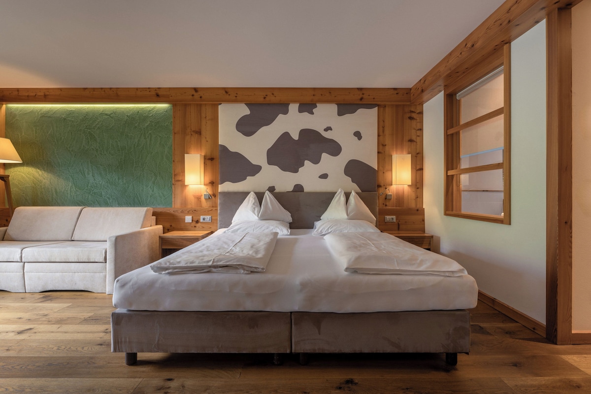 A bedroom with a large bed, a sofa, and wooden paneling.