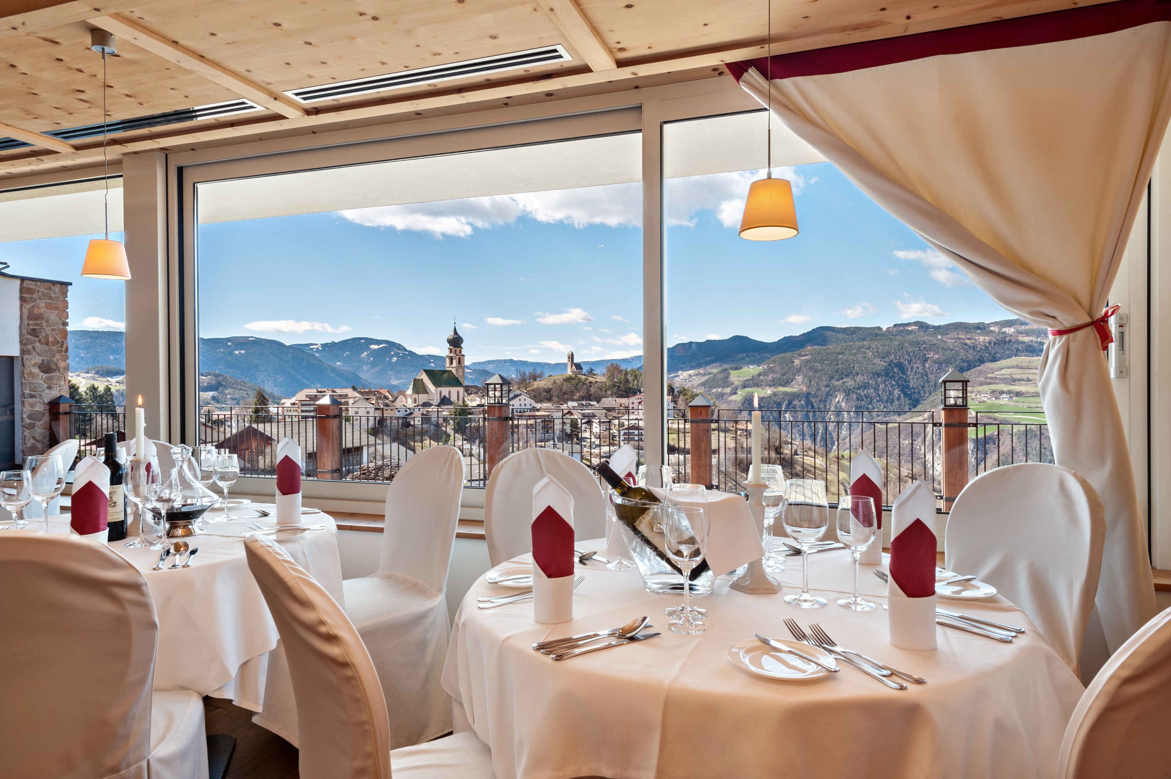 A restaurant with tables set for dining, featuring a scenic mountain view through large windows.