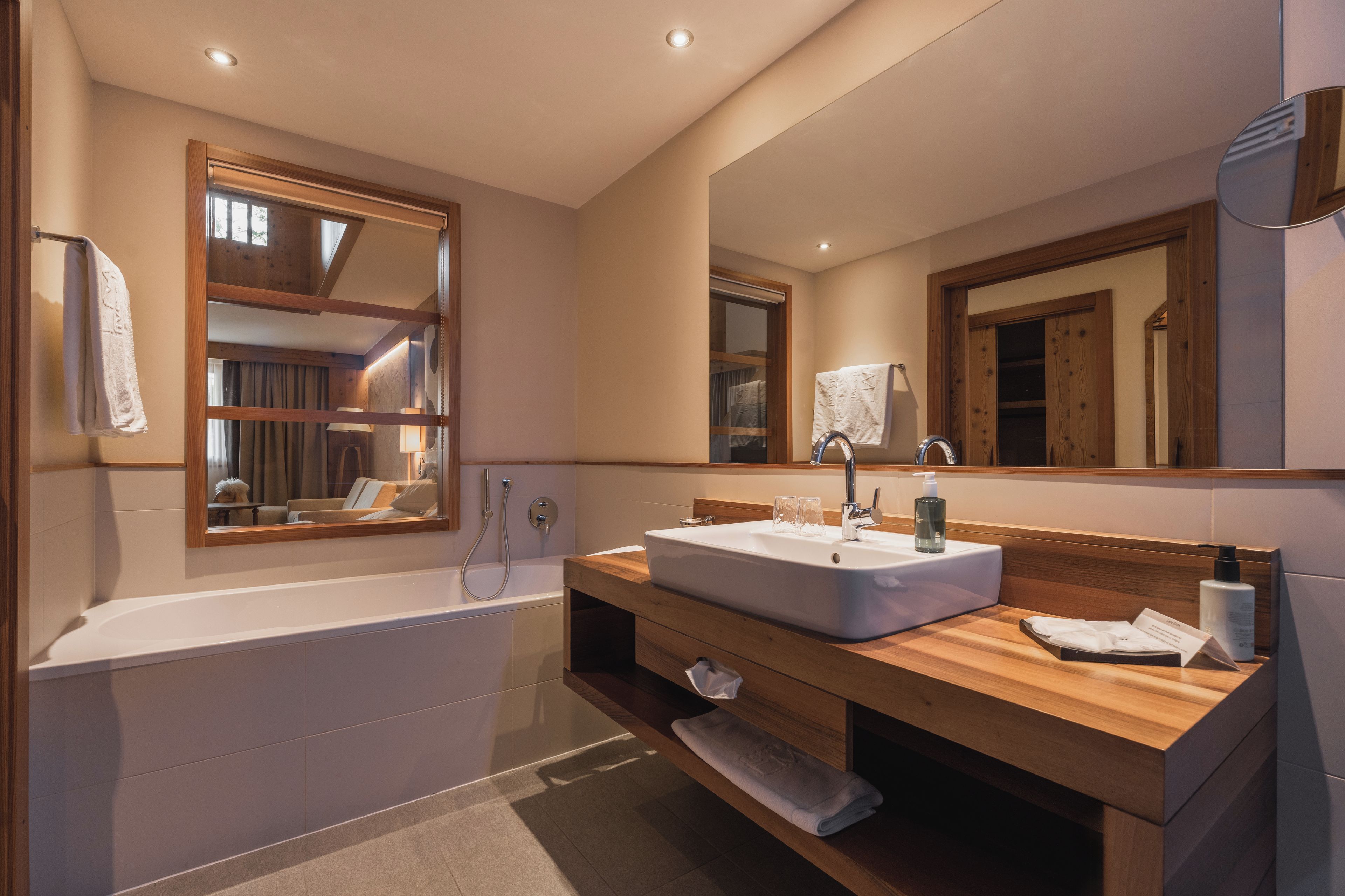 A modern bathroom with a freestanding bathtub, a large mirror, and a wooden vanity with a sink.