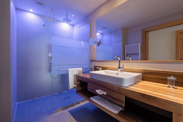 Une salle de bain moderne avec une douche à parois de verre, un grand lavabo et un meuble-lavabo en bois.