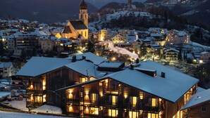 Un pueblo cubierto de nieve con una iglesia destacada y un edificio de madera con balcones.