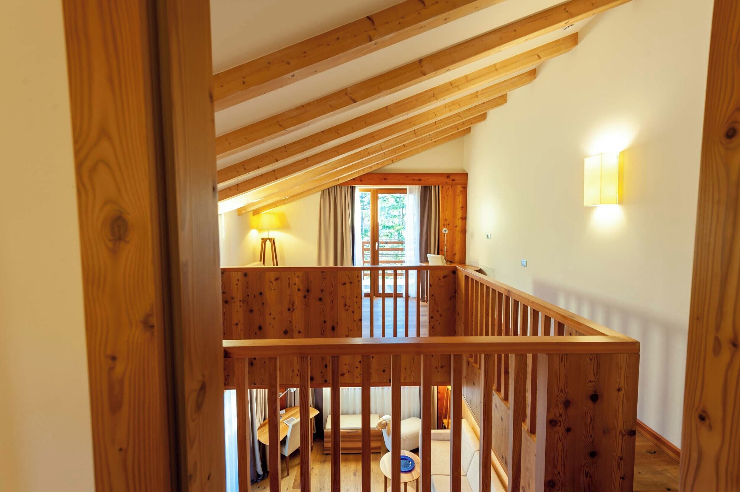 Una escalera de madera que lleva a un balcón con vistas a un jardín.