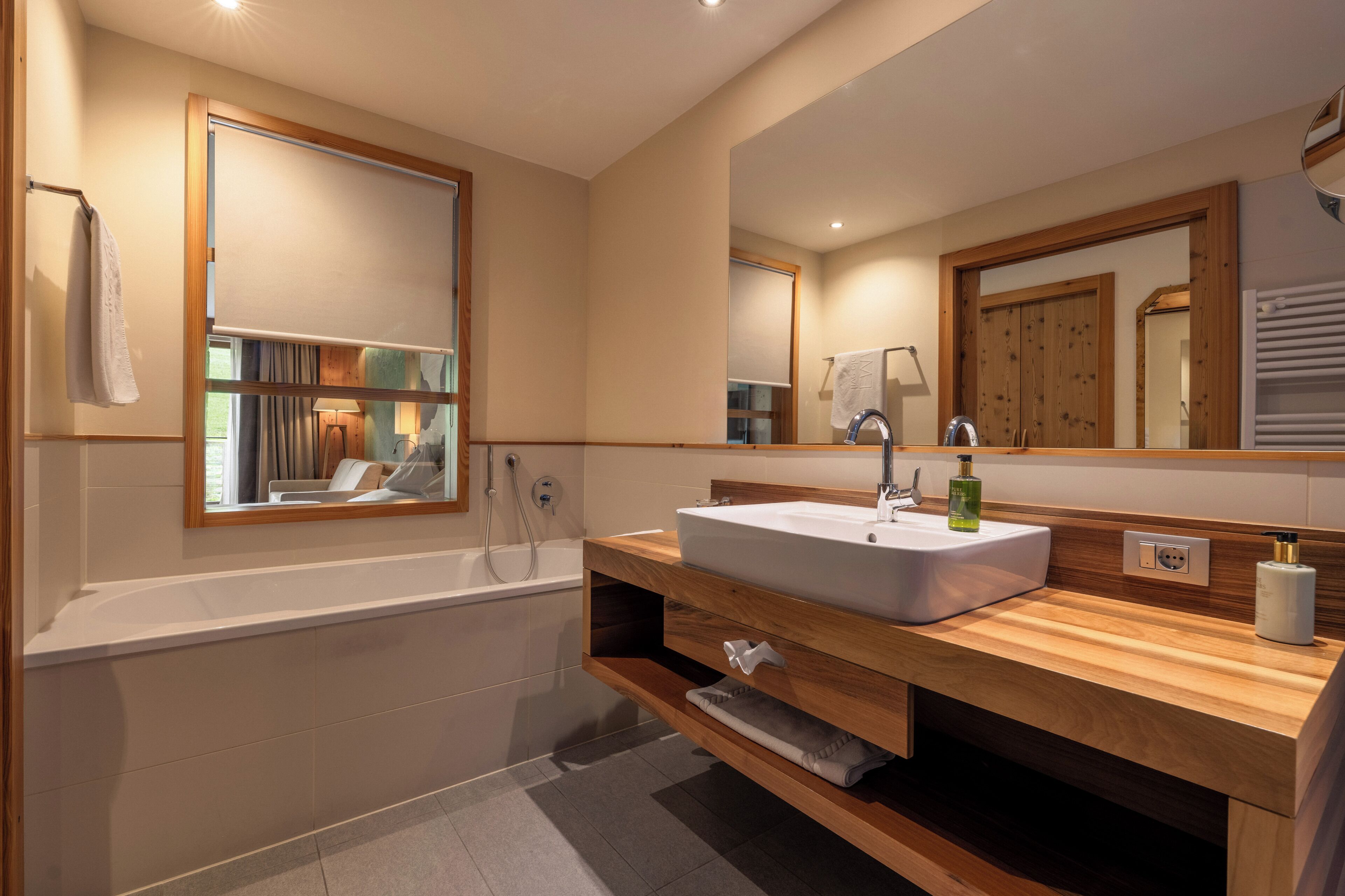 Ein modernes Badezimmer mit freistehender Badewanne, einem großen Spiegel und einem hölzernen Waschtisch.