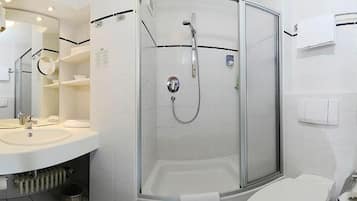 A modern bathroom with a glass-enclosed shower, a white sink, and a toilet.