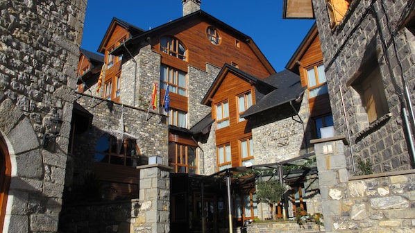 A traditional stone building with wooden upper floors, a stone entrance, and a clear blue sky.