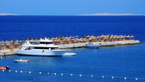 A marina with a large yacht docked, surrounded by beach umbrellas and lounge chairs. - Beach Albatros Resort - All Inclusive  (Hurghada)