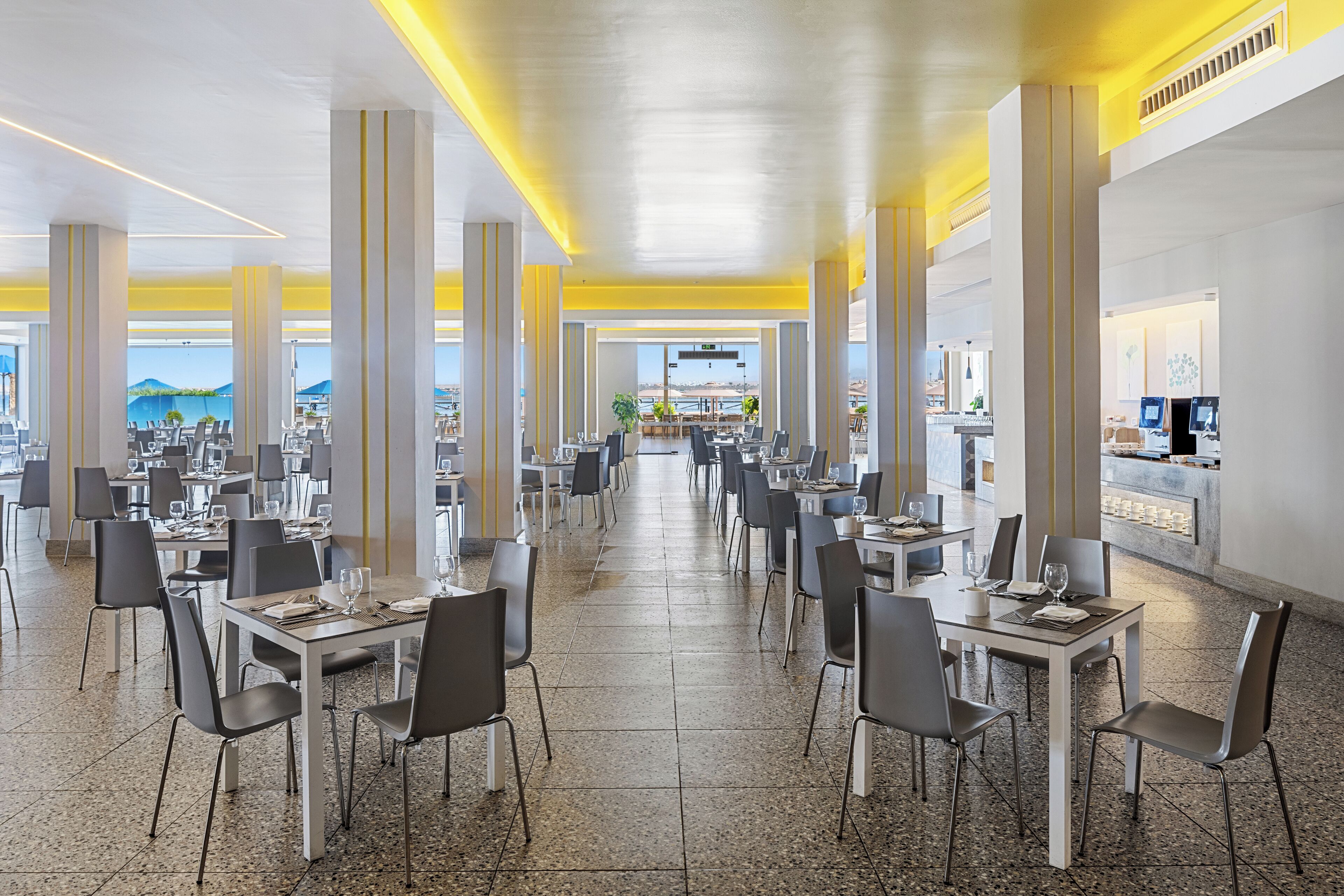 A spacious dining area with high ceilings, large windows, and a view of the mountains.
