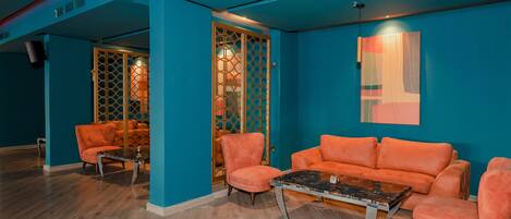 A room with teal walls, orange sofas, and a wooden floor.