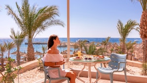 A woman seated at a table with a view of the sea and palm trees. - Beach Albatros Resort - All Inclusive  (Hurghada)
