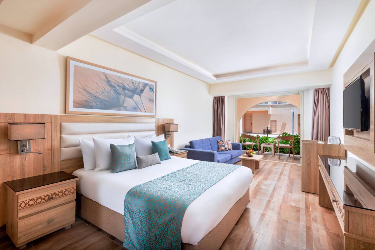 Une chambre d’hôtel avec un grand lit, un canapé, une télévision et un coin repas comprenant des chaises et une table.