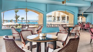 A restaurant with a view of the beach, featuring round tables and patterned chairs. - Beach Albatros Resort - All Inclusive  (Hurghada)