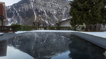 Een buitenzwembad, ligstoelen bij het zwembad