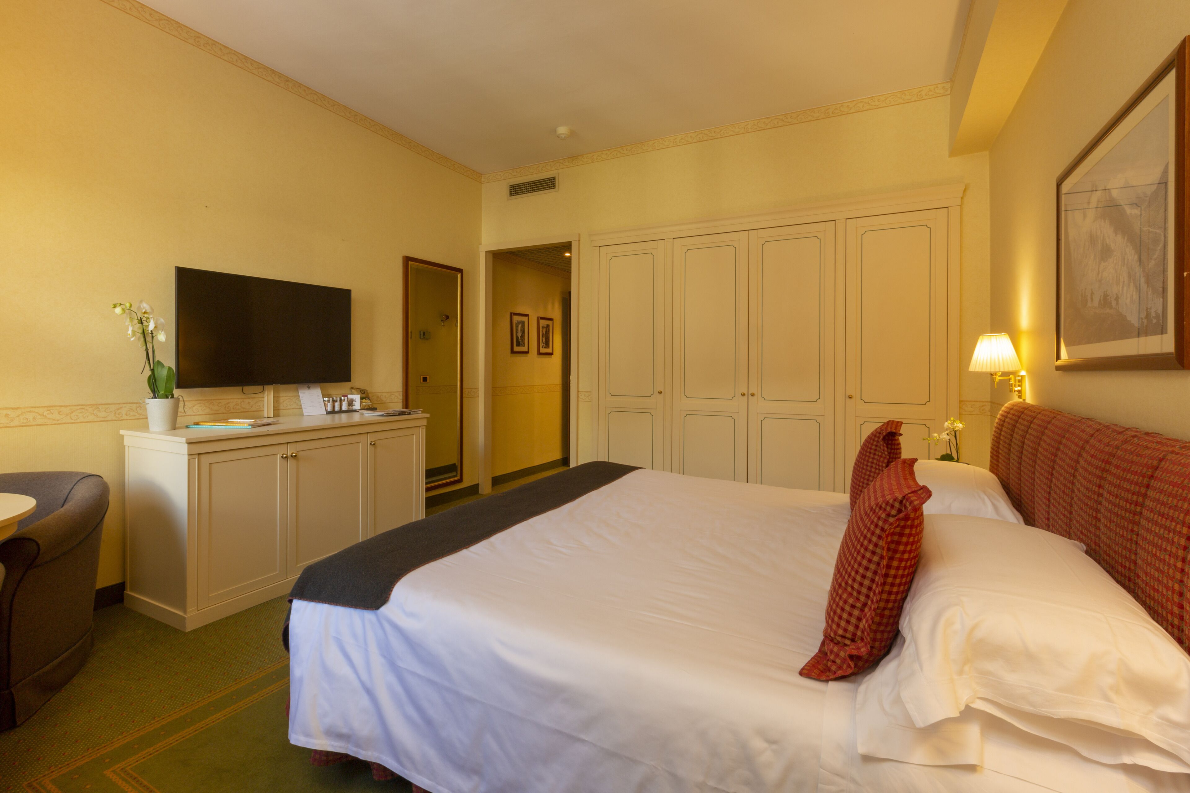 Una camera d'albergo con un letto grande, una televisione, una scrivania e una sedia.