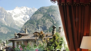 A table set for breakfast with a mountain view, including a newspaper, pastries, and a menu.