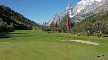 Enjoy a serene golfing experience with a clear view of the green and surrounding mountains.