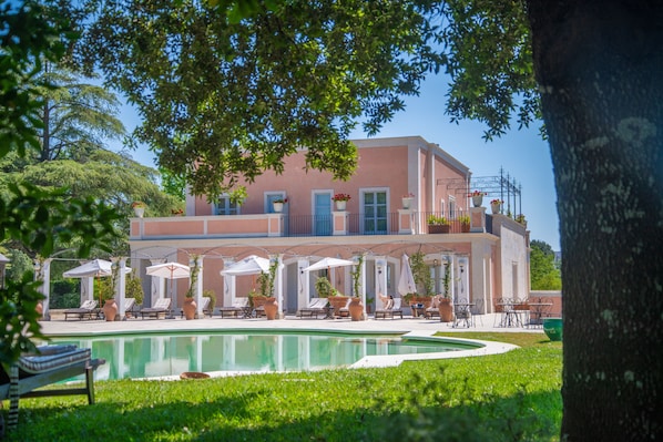 A building with a pool, outdoor seating, and potted plants. - Relais Villa San Martino (Martina Franca)