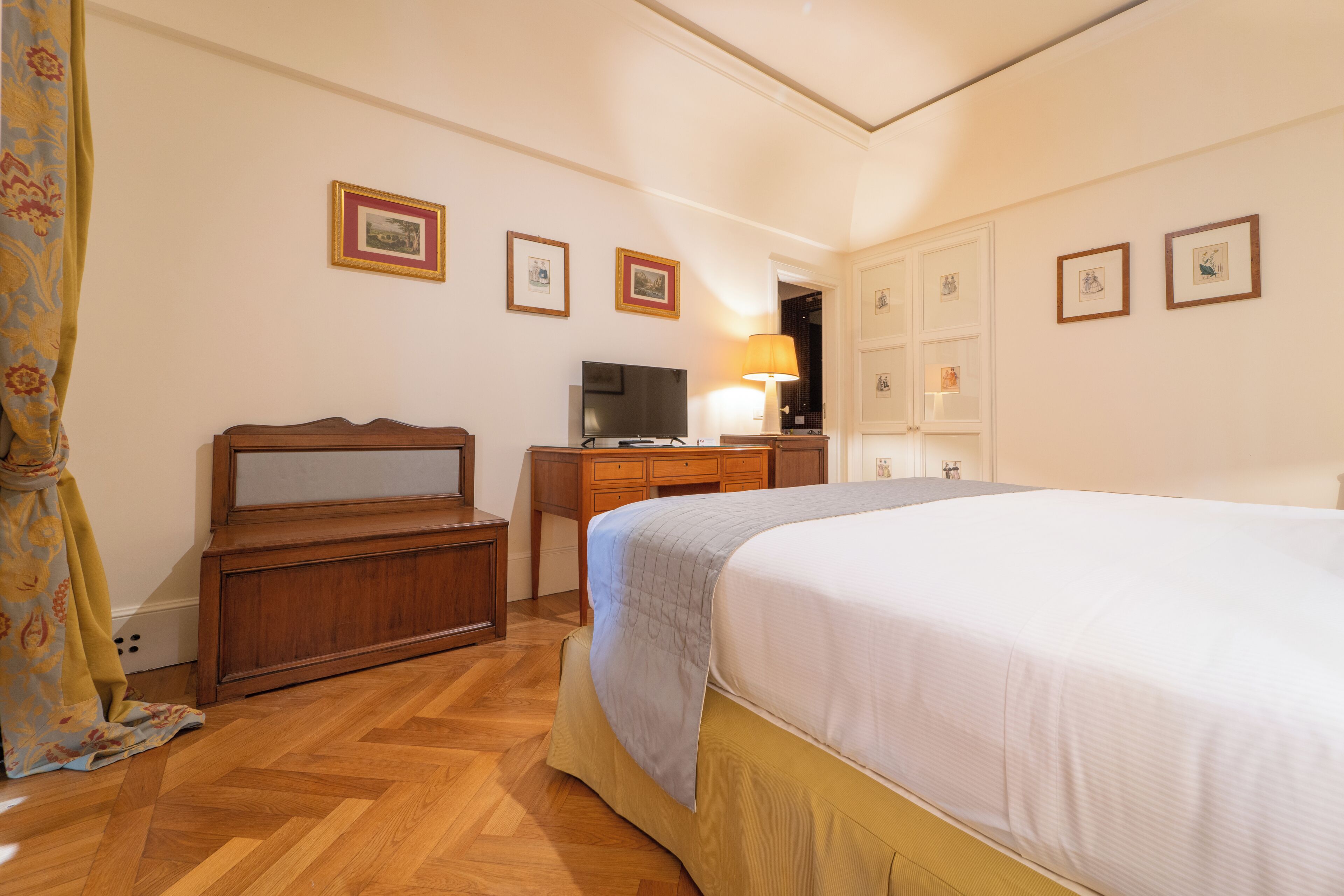 Une chambre d’hôtel avec un lit, un bureau, une télévision et une lampe.