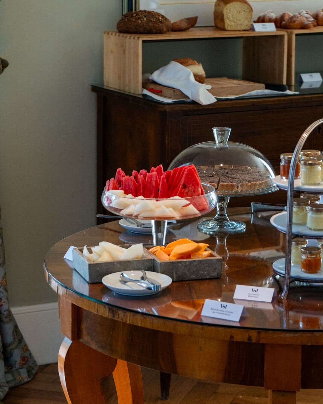 A breakfast buffet with various bread, fruits, and pastries.