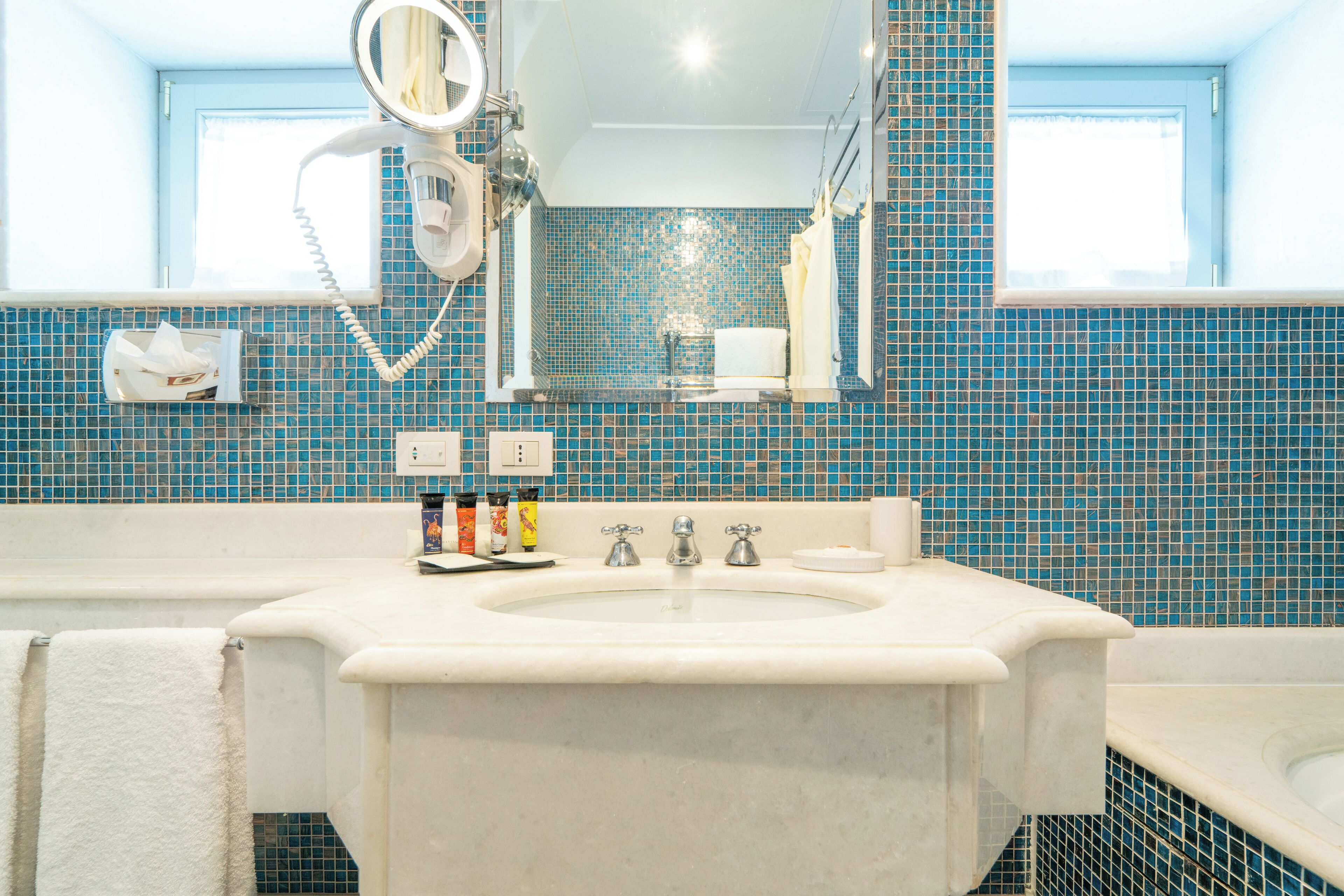 A bathroom with a sink, mirror, and blue-tiled walls.