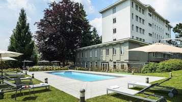 Una piscina al aire libre, sombrillas, sillones reclinables de piscina