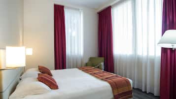 A hotel room with a large bed, a chair, and a lamp.
