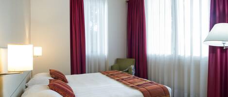 Una habitación de hotel con una cama grande, una silla y una lámpara.