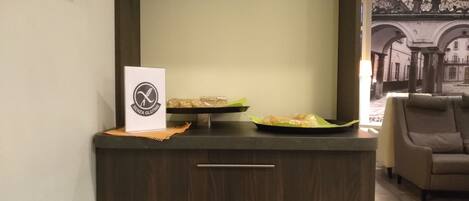 A modern interior with a dark wood cabinet, a sign reading "Senza Glutine," and a tray with packaged food items.
