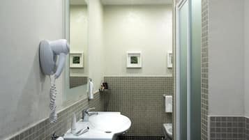 A bathroom with a white sink, a hairdryer mounted on the wall, and a mirror above the sink.