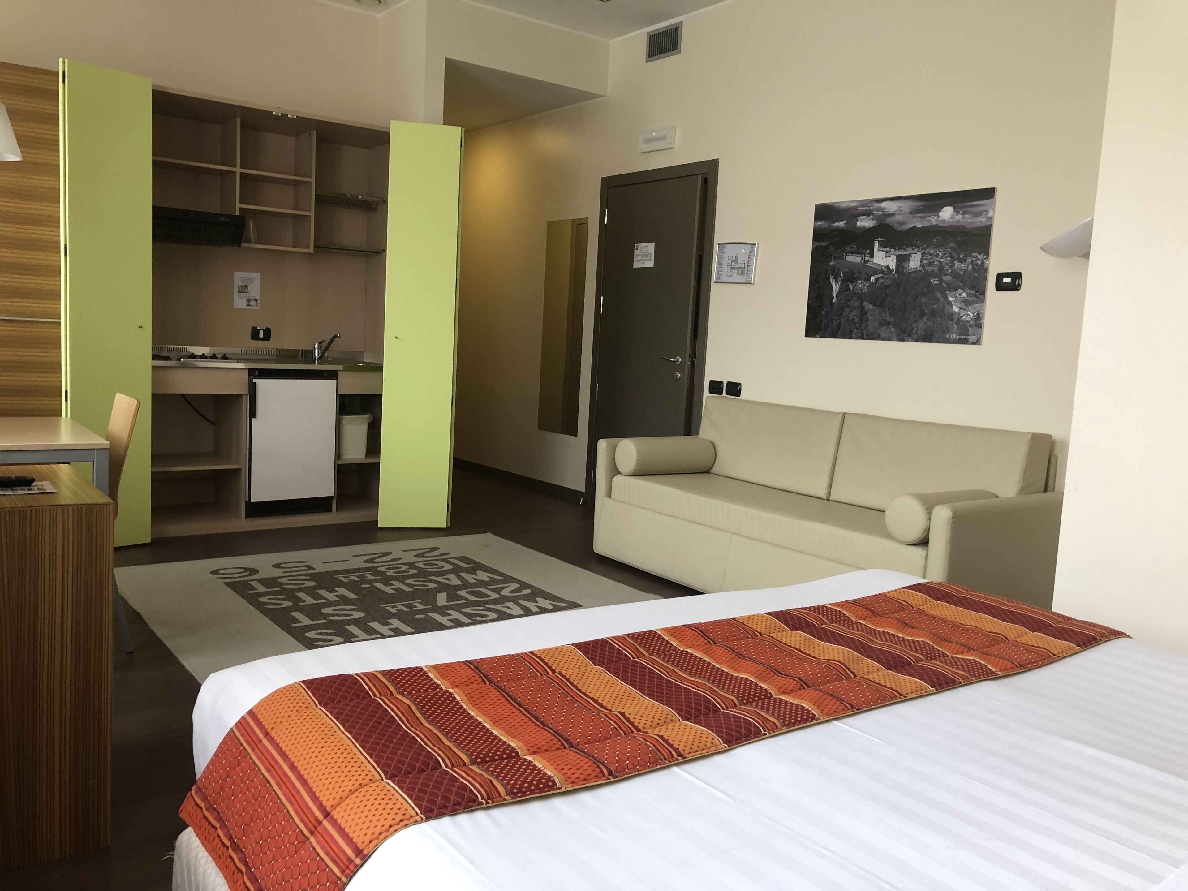 Ein Hotelzimmer mit Bett, einer Sitzecke, einer Küchenzeile und einem Essbereich.