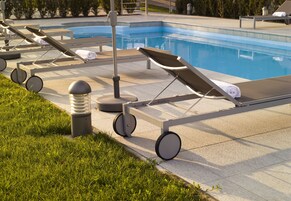 Un área junto a la piscina con sillones de descanso, una piscina y una zona de césped.