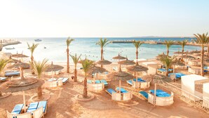 A beach resort with sun loungers, umbrellas, and a view of the sea.