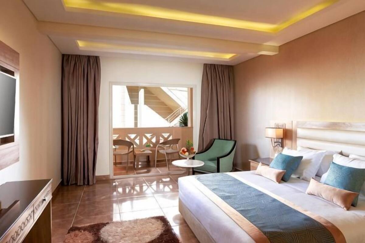 A hotel room with a bed, a TV, a desk, and a balcony.