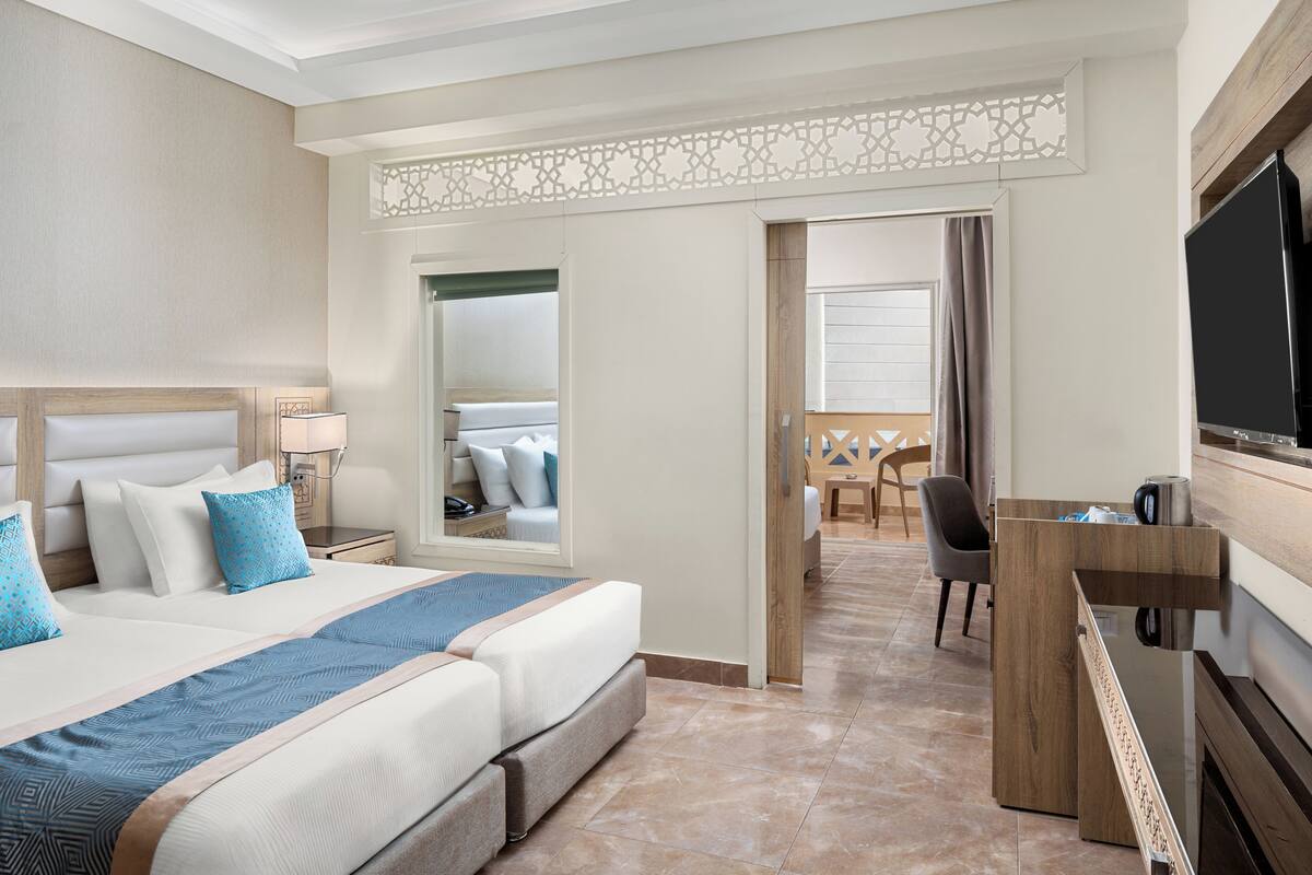 A hotel room with a large bed, a desk, a TV, and a bathroom visible through an open door.