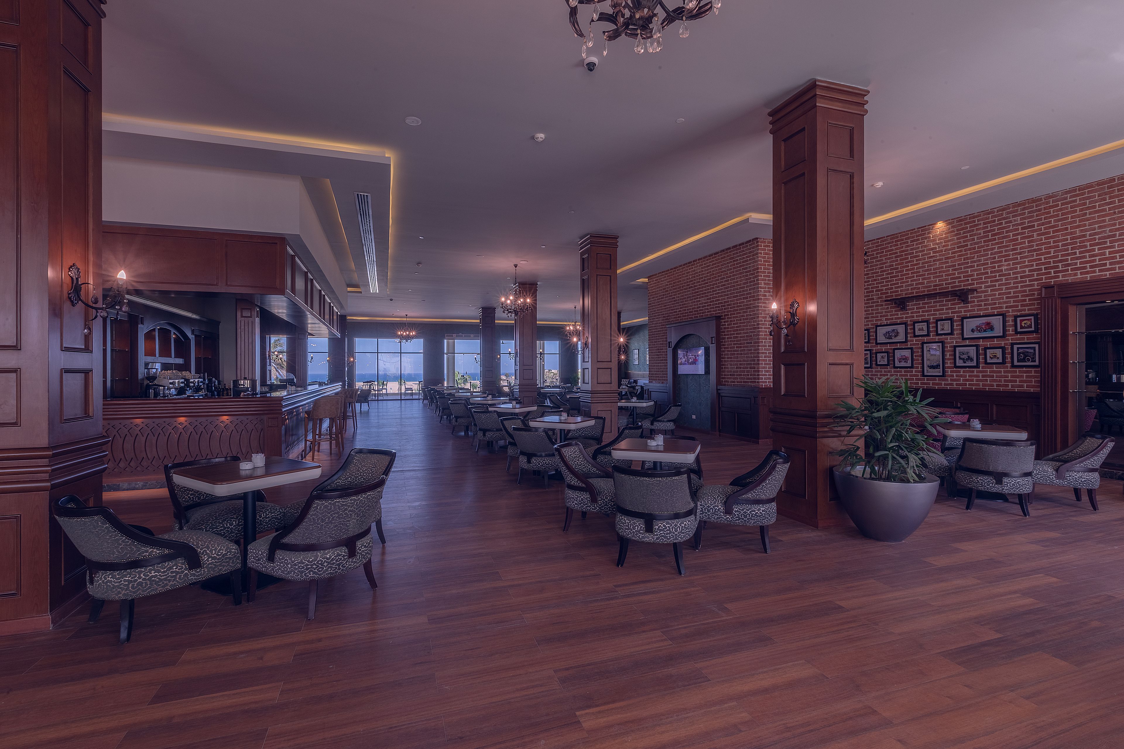 Un grand espace intérieur doté d’un plancher en bois, de plusieurs coins salon et d’un bar.