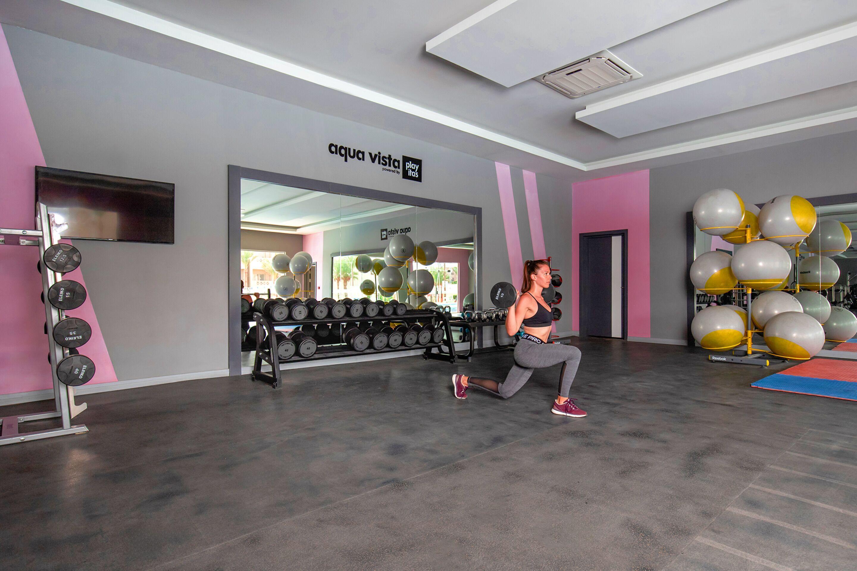 Een sportschool met trainingsapparatuur, een spiegel en een muur met een bord.